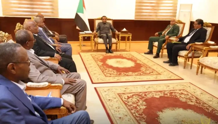 Officials seated in armchairs around a government meeting room with a Sudanese flag in the background.
